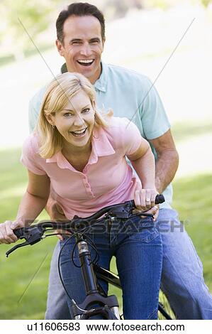 Couple on one bike outdoors smiling View Large Photo Image Stock Image - Couple on one bike outdoors smiling. Fotosearch