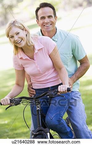 Couple on one bike outdoors smiling View Large Photo Image Stock Photo - Couple on one bike outdoors smiling. Fotosearch