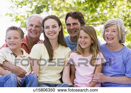 Extended family sitting outdoors smiling View Large Photo Image Stock Image - Extended family sitting outdoors smiling. Fotosearch