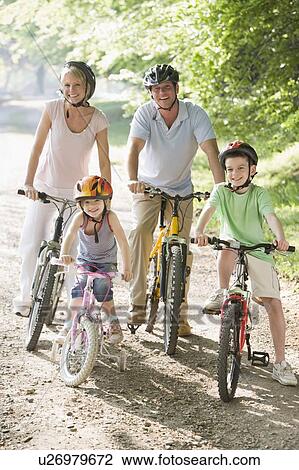 Stock Image - Family sitting on bikes on path smiling. Fotosearch