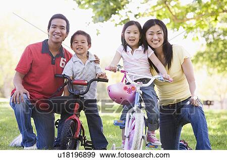 Family with children on bikes outdoors smiling View Large Photo Image Stock Photo - Family with children on bikes outdoors smiling. Fotosearch
