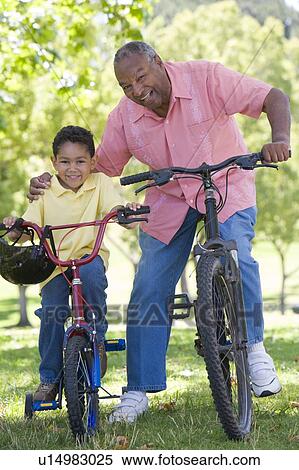 Stock Photography - Grandfather and grandson on bikes outdoors smiling. Fotosearch