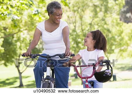 Grandmother and granddaughter on bikes outdoors smiling View Large Photo Image Stock Image - Grandmother and granddaughter on bikes outdoors smiling. Fotosearch