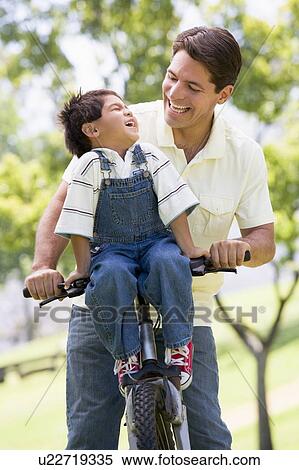 Man and young boy on a bike outdoors smiling View Large Photo Image Stock Photography - Man and young boy on a bike outdoors smiling. Fotosearch