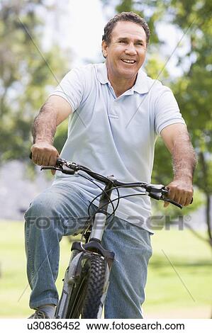 Man on bike outdoors smiling View Large Photo Image Stock Image - Man on bike outdoors smiling. Fotosearch