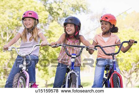 Three young girl friends outdoors on bicycles smiling View Large Photo Image Stock Photo - Three young girl friends outdoors on bicycles smiling. Fotosearch