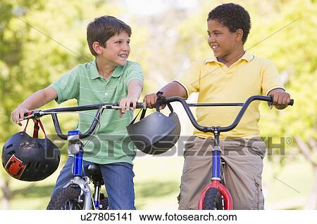 Two young boys on bicycles outdoors smiling View Large Photo Image Stock Image - Two young boys on bicycles outdoors smiling. Fotosearch