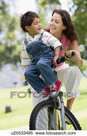 Woman and young boy on a bike outdoors smiling View Large Photo Image Stock Photography - Woman and young boy on a bike outdoors smiling. Fotosearch