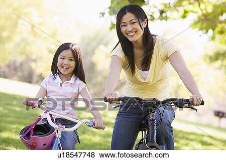 Woman and young girl on bikes outdoors smiling View Large Photo Image Stock Photo - Woman and young girl on bikes outdoors smiling. Fotosearch