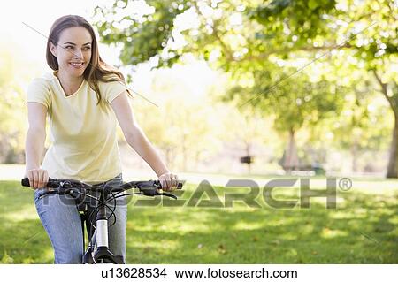 Woman on bicycle smiling View Large Photo Image Picture - Woman on bicycle smiling. Fotosearch