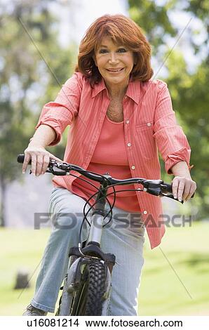 Woman on bike outdoors smiling View Large Photo Image Picture - Woman on bike outdoors smiling. Fotosearch