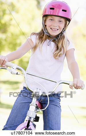 Picture - Young girl on bicycle outdoors smiling. Fotosearch