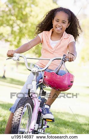 Young girl on bicycle outdoors smiling View Large Photo Image Stock Photo - Young girl on bicycle outdoors smiling. Fotosearch