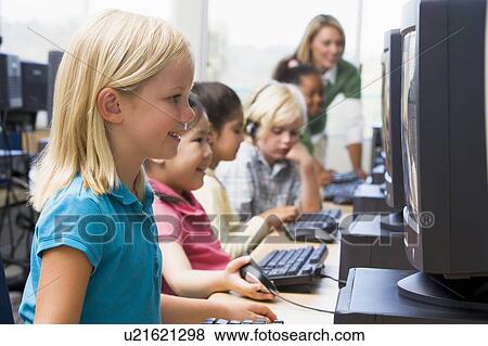 Stock Photo - Children at computer terminals with teacher in background (depth of field/high key). Fotosearch