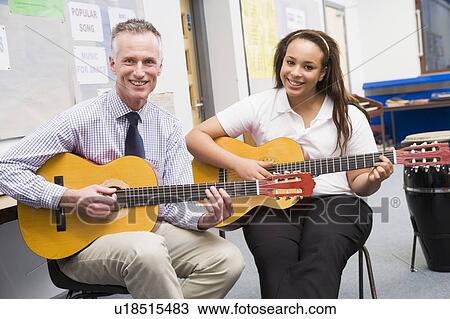 Female student receiving guitar lesson from teacher in classroom View Large Photo Image Stock Image - Female student receiving guitar lesson from teacher in classroom. Fotosearch