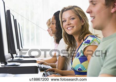 Stock Image - Four people sitting at computer terminals (selective focus/high key). Fotosearch