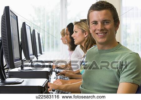 Stock Photograph - Four people sitting at computer terminals (depth of field/high key). Fotosearch