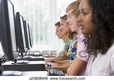 Stock Photograph - Four people sitting at computer terminals (selective focus/high key). Fotosearch