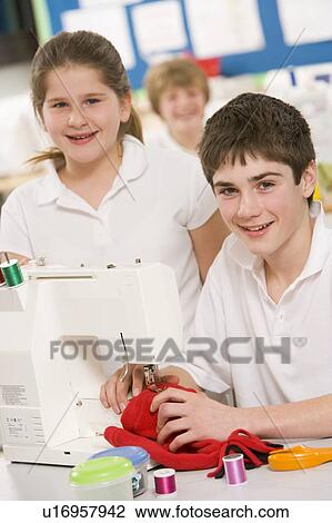 Stock Image - Male and female student using sewing machine. Fotosearch