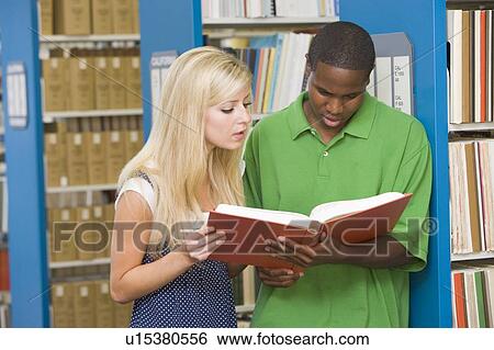 Stock Photograph - Man and woman in library reading book (depth of field). Fotosearch