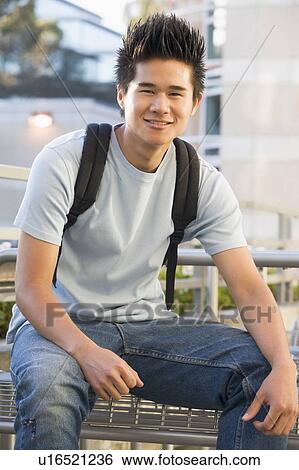 Stock Photograph - Man sitting on bench outdoors smiling (selective focus). Fotosearch