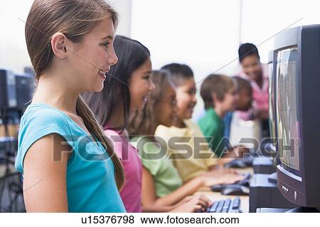 Stock Photo - Six children at computer terminals with teacher in background (depth of field/high key). Fotosearch