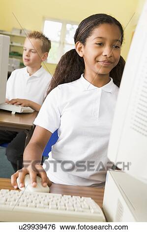 Stock Photograph - Student at computer terminal with student in background (selective focus). Fotosearch