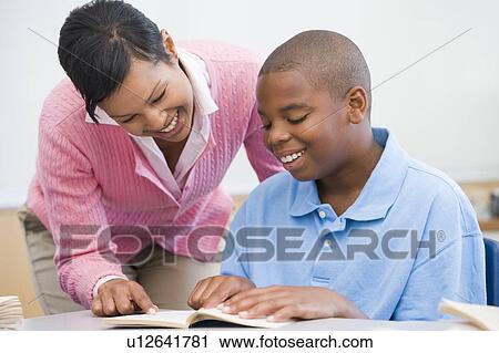 Stock Image - Student in class reading with teacher. Fotosearch