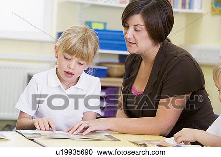 Stock Image - Student in class with teacher reading. Fotosearch