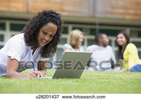 Student outdoors on lawn using laptop with other students in background (selective focus) View Large Photo Image Stock Photo - Student outdoors on lawn using laptop with other students in background (selective focus). Fotosearch