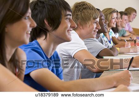 Stock Photo - Students in class paying attention and taking notes (selective focus). Fotosearch