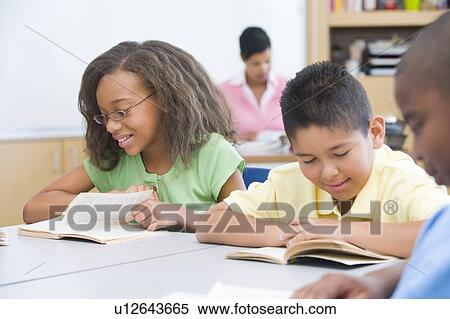 Students in class reading with teacher in background (selective focus) View Large Photo Image Stock Photography - Students in class reading with teacher in background (selective focus). Fotosearch