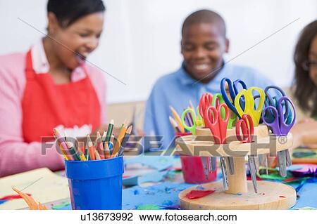 Stock Image - Teacher and student in art class with supplies in foreground (selective focus). Fotosearch