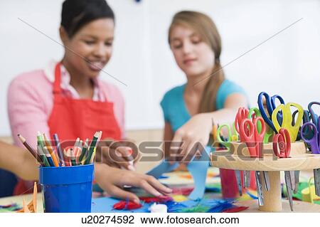 Stock Image - Teacher and student in art class with supplies in foreground (selective focus). Fotosearch