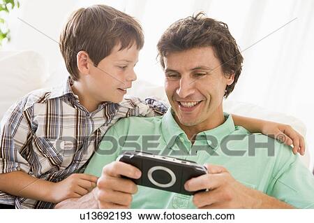 Man and young boy with handheld game smiling View Large Photo Image Stock Image - Man and young boy with handheld game smiling. Fotosearch