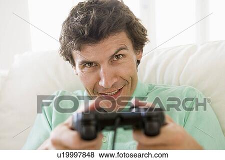 Man in living room playing videogames smiling View Large Photo Image Stock Photo - Man in living room playing videogames smiling. Fotosearch