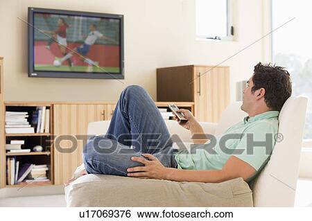 Stock Photograph - Man in living room watching television. Fotosearch