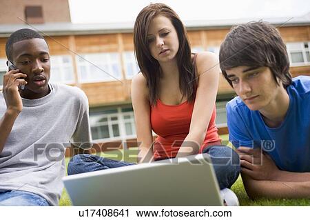 Three students outdoors on lawn with laptop one on cellular phone View Large Photo Image Stock Image - Three students outdoors on lawn with laptop one on cellular phone. Fotosearch