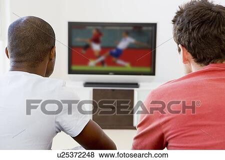 Two men in living room watching television View Large Photo Image Stock Photo - Two men in living room watching television. Fotosearch