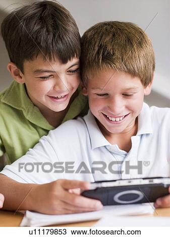 Two Young Boys Playing With A Handheld Video Game View Large Photo Image Stock Image - Two Young Boys Playing With A Handheld Video Game. Fotosearch