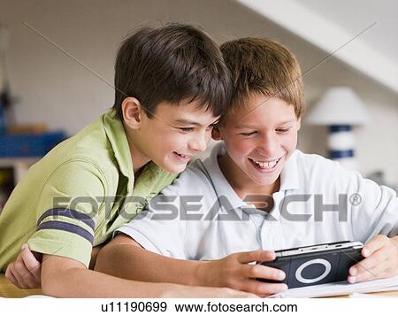 Stock Photo - Two Young Boys Playing With A Handheld Video Game. Fotosearch