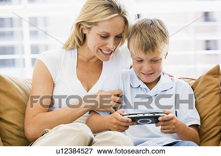 Woman and young boy in living room with handheld video game smiling View Large Photo Image Stock Photo - Woman and young boy in living room with handheld video game smiling. Fotosearch