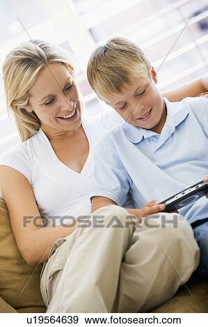 Woman and young boy in living room with handheld video game smiling View Large Photo Image Stock Photo - Woman and young boy in living room with handheld video game smiling. Fotosearch