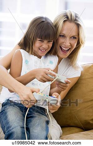 Woman and young girl in living room with video game controllers smiling View Large Photo Image Stock Image - Woman and young girl in living room with video game controllers smiling. Fotosearch