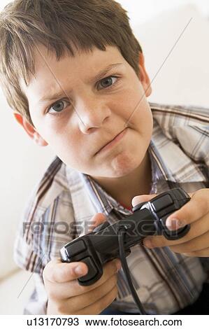 Young boy holding video game controller looking confused View Large Photo Image Stock Image - Young boy holding video game controller looking confused. Fotosearch