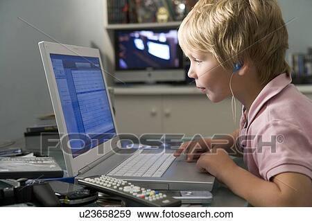 Young boy in bedroom using laptop and listening to MP3 player View Large Photo Image Stock Photo - Young boy in bedroom using laptop and listening to MP3 player. Fotosearch