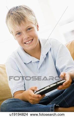 Young boy in living room with handheld video game smiling View Large Photo Image Picture - Young boy in living room with handheld video game smiling. Fotosearch