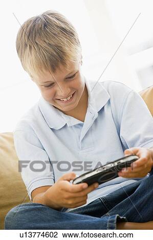 Young boy in living room with handheld video game smiling View Large Photo Image Stock Image - Young boy in living room with handheld video game smiling. Fotosearch