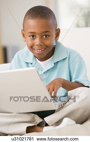 Young boy in living room with laptop smiling View Large Photo Image Stock Image - Young boy in living room with laptop smiling. Fotosearch
