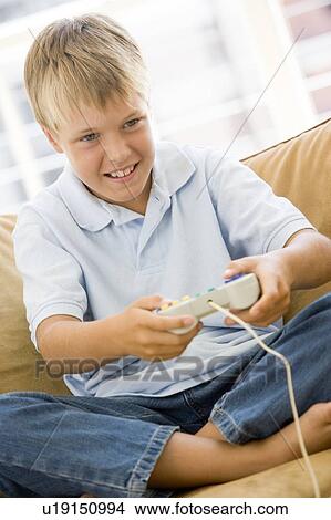Young boy in living room with video game controller smiling View Large Photo Image Picture - Young boy in living room with video game controller smiling. Fotosearch